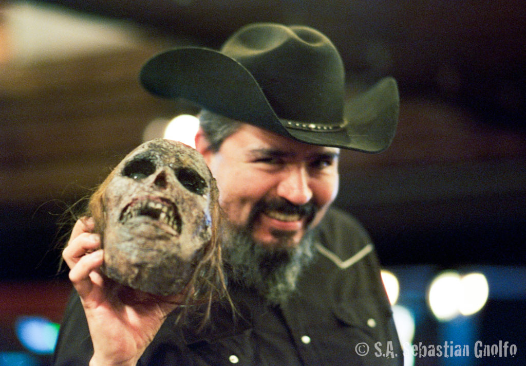 Picture of a man holding a dessicated skull in one hand